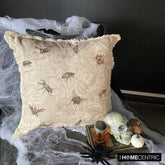 Decorative pillow with a vintage insect design, including flies, beetles, and bees, placed beside a skull, jar, and pumpkin for a spooky Halloween setting.