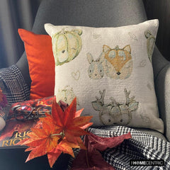 Fall Halloween home decor pillow cover, A woven jacquard throw pillow cover with pumpkin fox design and subtle fall colors for Autumn Decor set on a grey chair with a black throw and layered with an orange velvet pillow cover. Decorated with a tray containing maple leaves, pumpkin, book, and fall colored flowers, creating a perfect, cozy, and comfortable fall decor setting. Handcrafted pillow cover from The HomeCentric's Fall Collection.