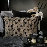 Halloween pillow with black spider embroidery surrounded by spooky decor, including a skeleton figure and foggy cauldrons.