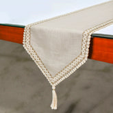 Beige linen table runner with lace trim draped over dining table