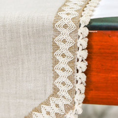 Close-up of knotted tassel fringe on beige linen table runner