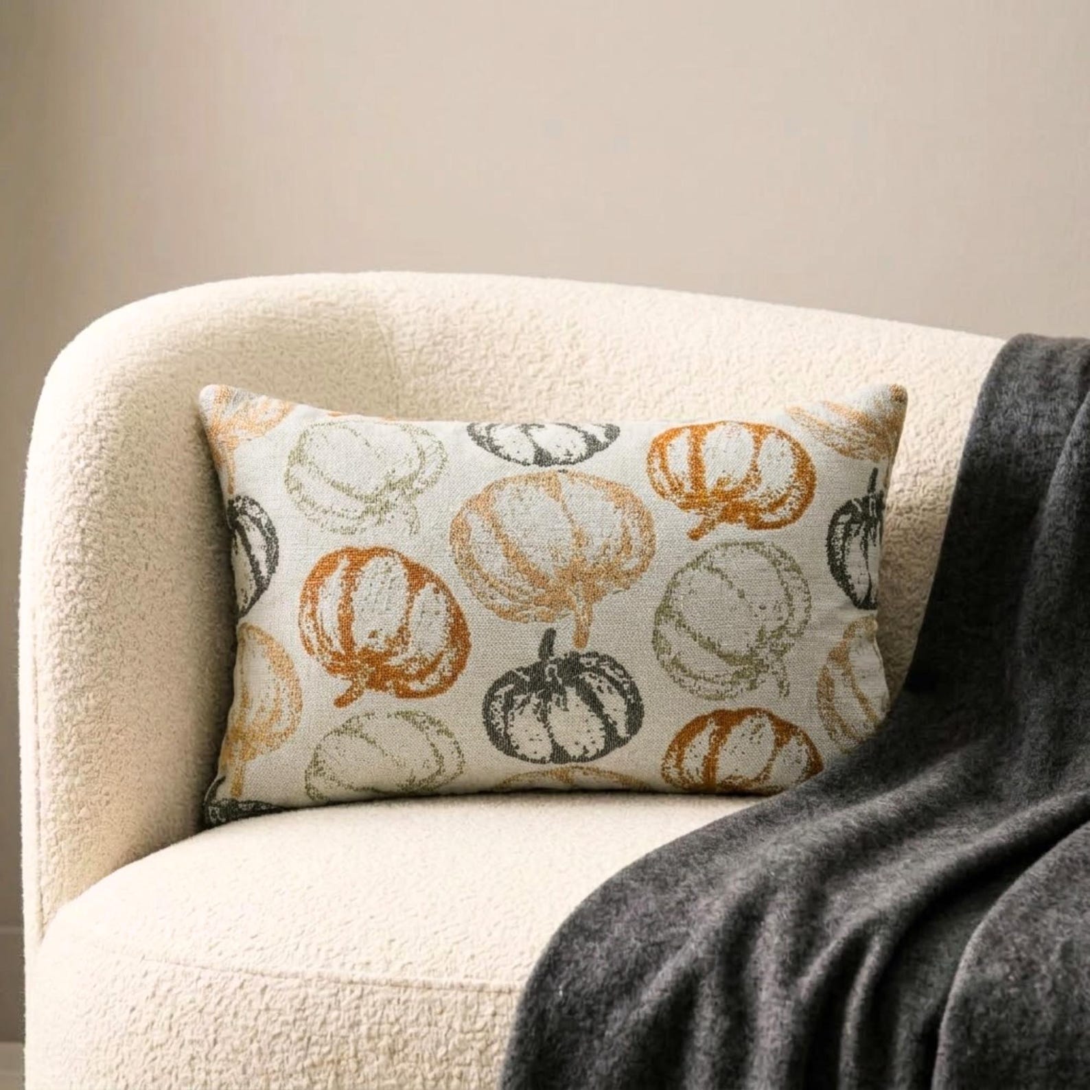 Orange woven jacquard pumpkin pattern lumbar pillow cover for Halloween & Fall home decor. Ideal for modern or country style home decor, the oblong cushion cover is set on a grey chair paired with a solid orange velvet throw pillow cover from The HomeCentric. A tray is place with the pillows on chair with maple leaves, burlap pumpkins and flower arrangement in fall hues. The look is finished with a black and white monochrome checkered throw. Explore more of fall & Halloween Collection by The HomeCentric!