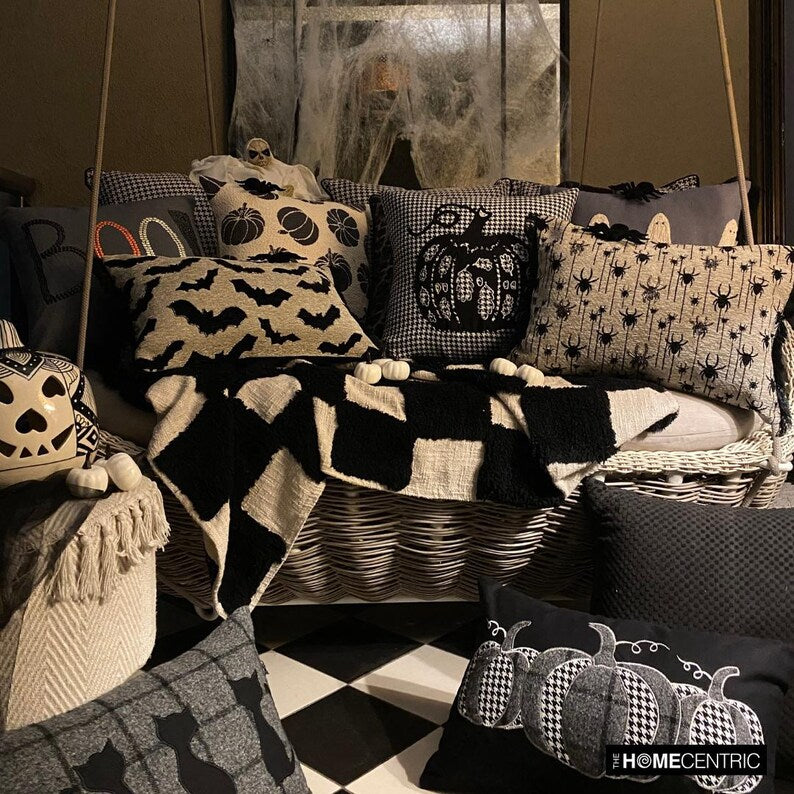 Cozy Halloween decorative pillow covers display with various spooky, haunting and scary Halloween themed placed in a cozy setting with pumpkin decor and spider web.
