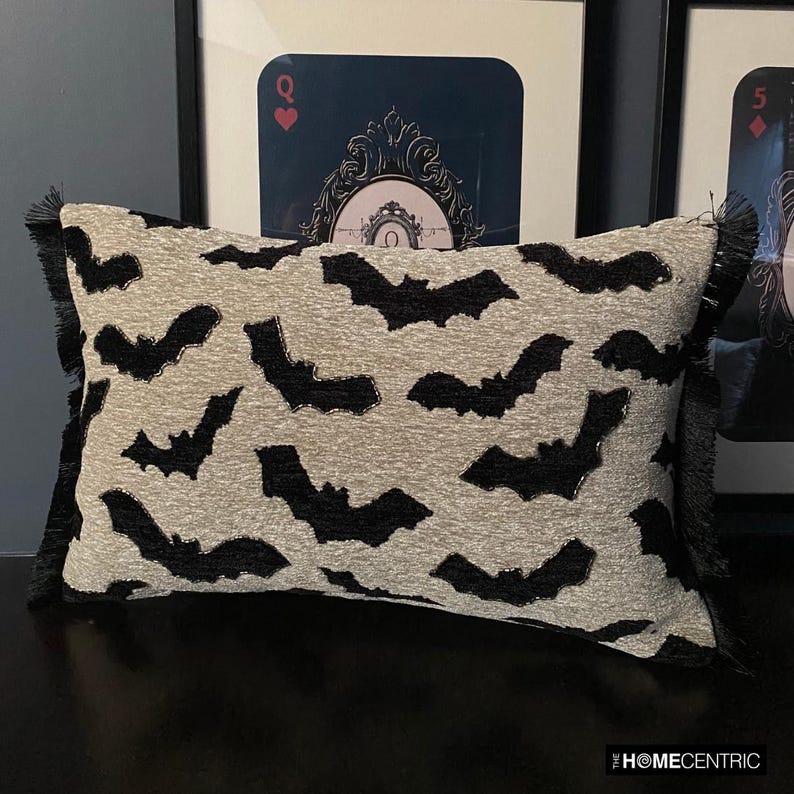 A Halloween-themed display featuring a decorative pillow with a gothic bat pattern on a brown surface surrounded by a card theme frame. 
