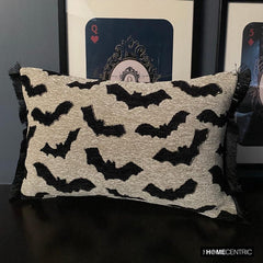 A Halloween-themed display featuring a decorative pillow with a gothic bat pattern on a brown surface surrounded by a card theme frame. 