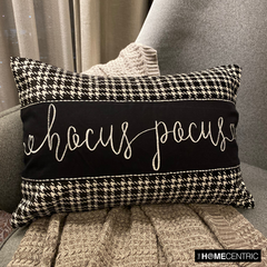 Close-up shot of a 'Hocus Pocus' black and white cotton houndstooth rectangle pillow cover on a couch with a gray throw.