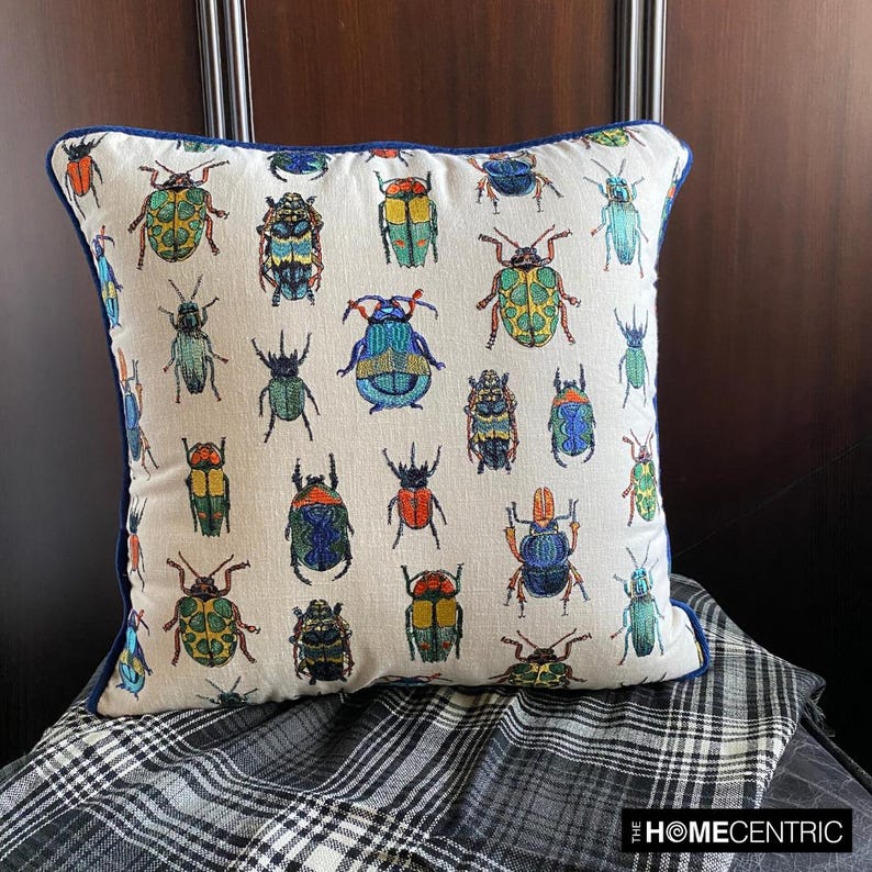 Beetle-printed pillow cover on a black chair with a checkered blanket, perfect for an eclectic home decor look.