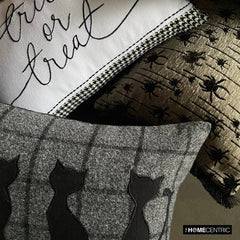 Halloween pillows stacked together, including a black cat design pillow, with a 'trick or treat' pillow and a spider-themed pillow