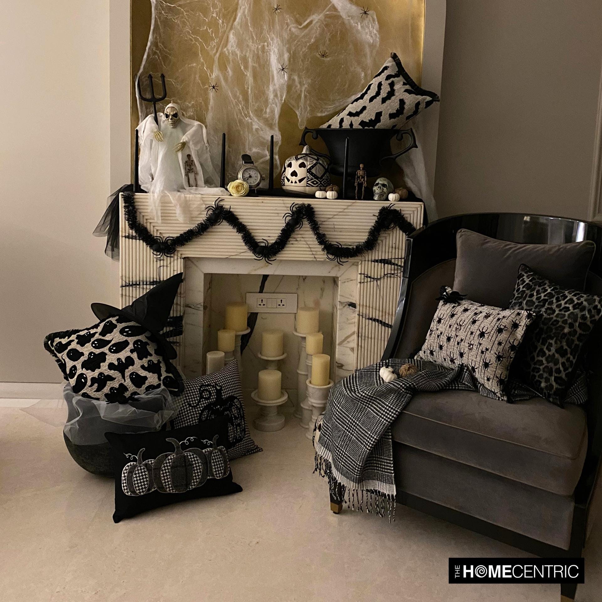 Halloween fireplace setting with spooky pillows featuring bat, Halloween ghosts and pumpkin motifs, draped with black decor around the fireplace. 