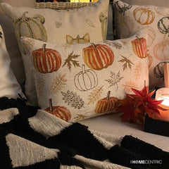 Orange, beige & ivory color pumpkin pattern with maple leaves lumbar pillow cover crafted on a woven jacquard fabric for fall & Halloween decor from The HomeCentric's autumn decor collection. The oblong cushion cover is set on a swing for a cozy autumn corner, beautifully set with fall theme pillows and a black & white throw, a tray with candle, maple leaves, & few burlap pumpkins. Creating a cozy and inviting autumn corner for peaceful moments during the season.  