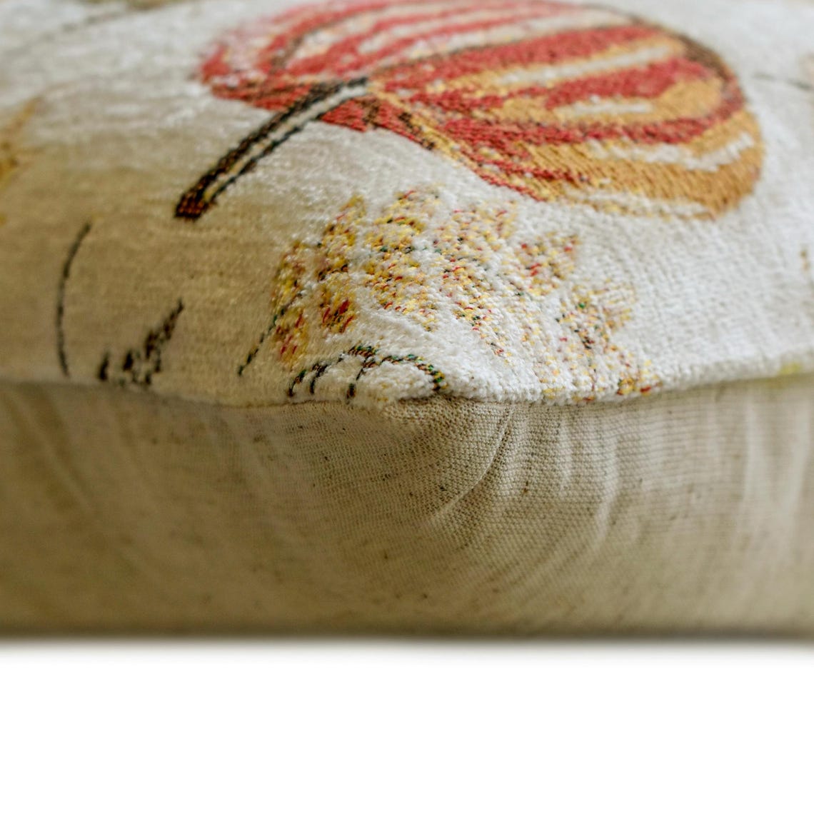 Olive green maple leaves, orange pumpkins, beige woven jacquard decorative oblong cushion cover by The HomeCentric for rustic country homes featured on a white background with a side view showcasing the texture of the pillow cover. 