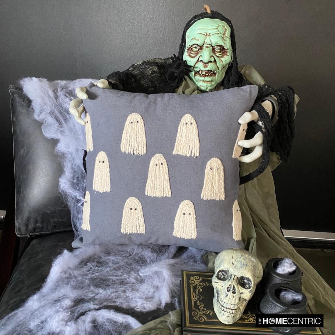 Embroidered ghost design pillow on a gray fabric. 