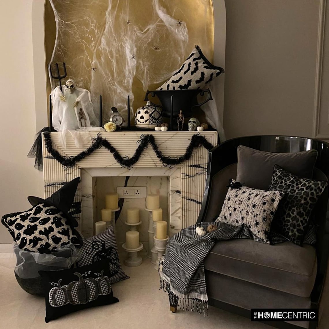 Halloween fireplace corner decorated with various spooky themed pillow covers including ghost, bats, spiders and pumpkin designs. Decorated with Halloween fireplace decor with witch pot and a witch hat, with scary Halloween ghost, black candles and tiny skulls and pumpkins. 