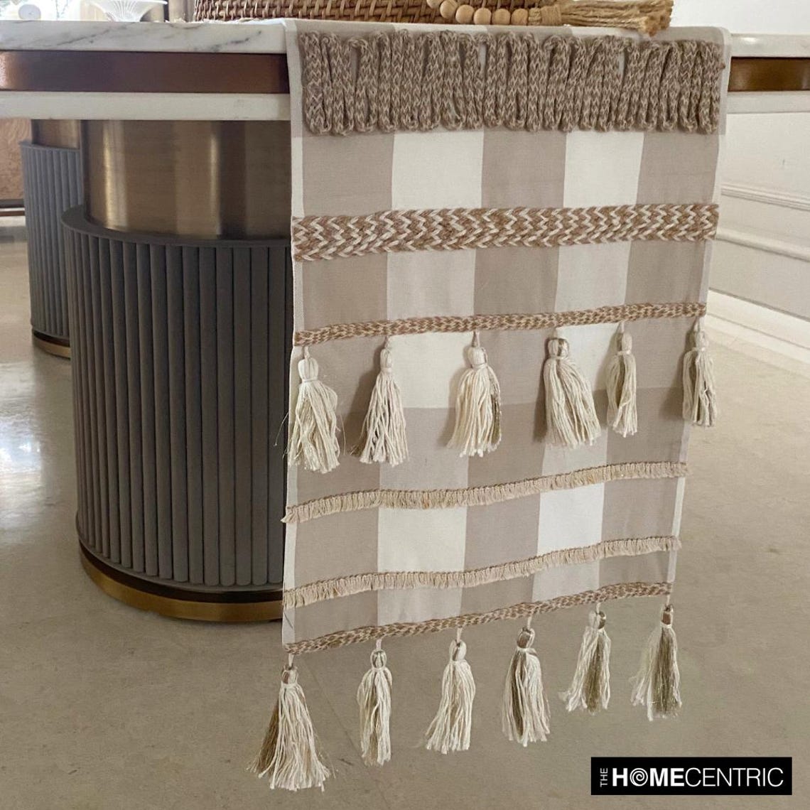 Side view of beige cotton table runner with tassels hanging over table edge