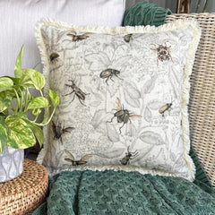 Decorative pillow with a vintage insect design, including flies, beetles, and bees, placed beside a skull, jar, and pumpkin for a spooky Halloween setting.