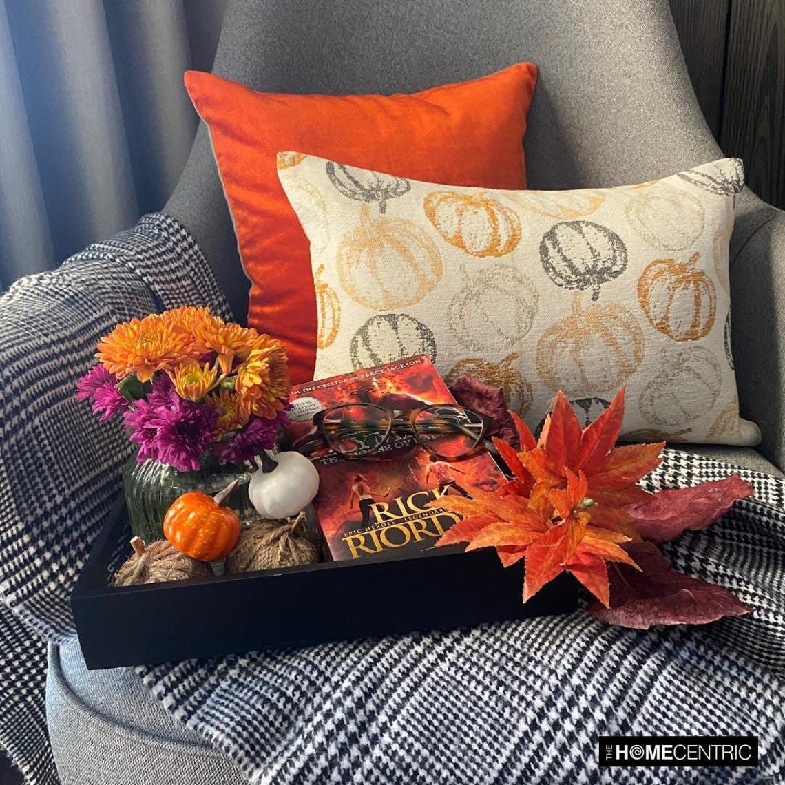 Orange woven jacquard pumpkin pattern lumbar pillow cover for Halloween & Fall home decor. Ideal for modern or country style home decor, the oblong cushion cover is set on a grey chair paired with a solid orange velvet throw pillow cover from The HomeCentric. A tray is place with the pillows on chair with maple leaves, burlap pumpkins and flower arrangement in fall hues. The look is finished with a black and white monochrome checkered throw. Explore more of fall & Halloween Collection by The HomeCentric!