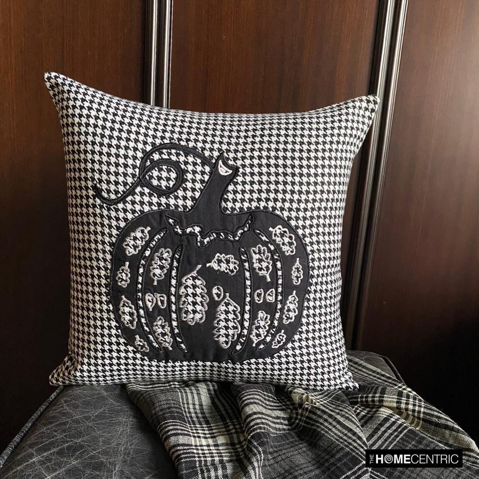 Cozy Halloween decorative pillow covers display with various spooky, haunting and scary Halloween themed placed in a cozy setting with pumpkin decor and spider web.