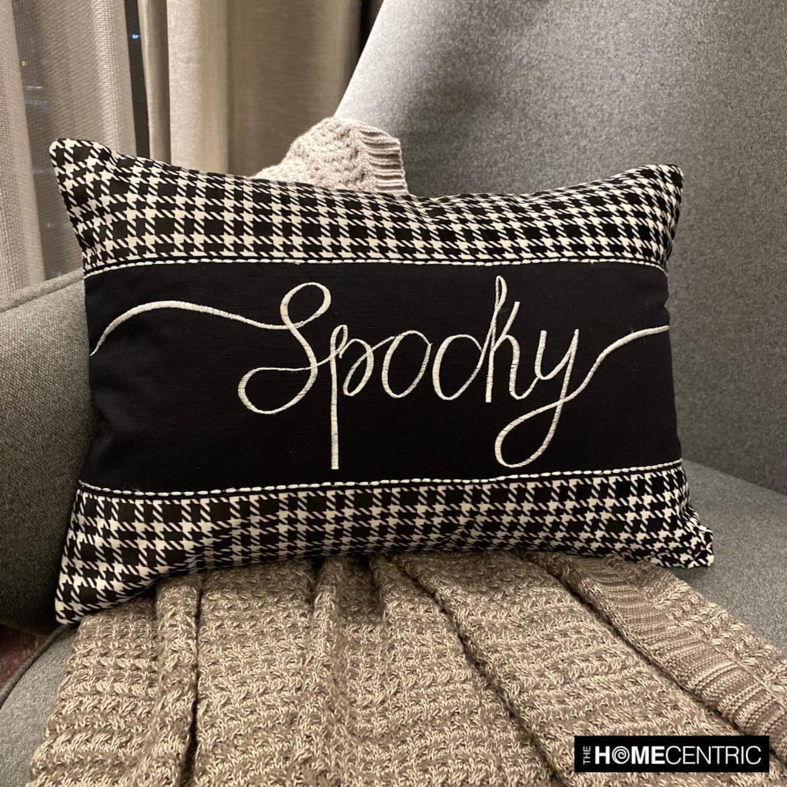 Simple yet spooky Halloween throw pillow with the word 'Spooky' in white script against a black and white houndstooth pattern, perfect for Halloween home decor.