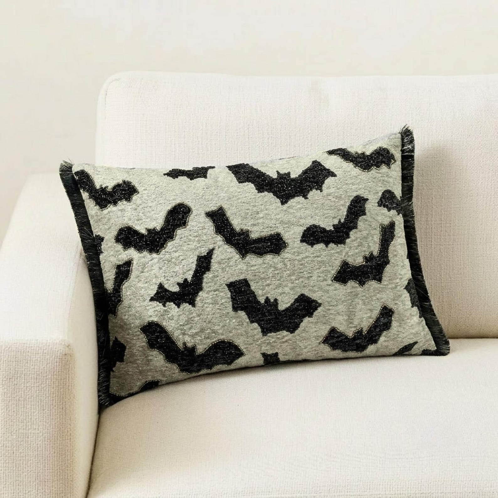 A Halloween-themed display featuring a decorative pillow with a gothic bat pattern on a brown surface surrounded by a card theme frame. 